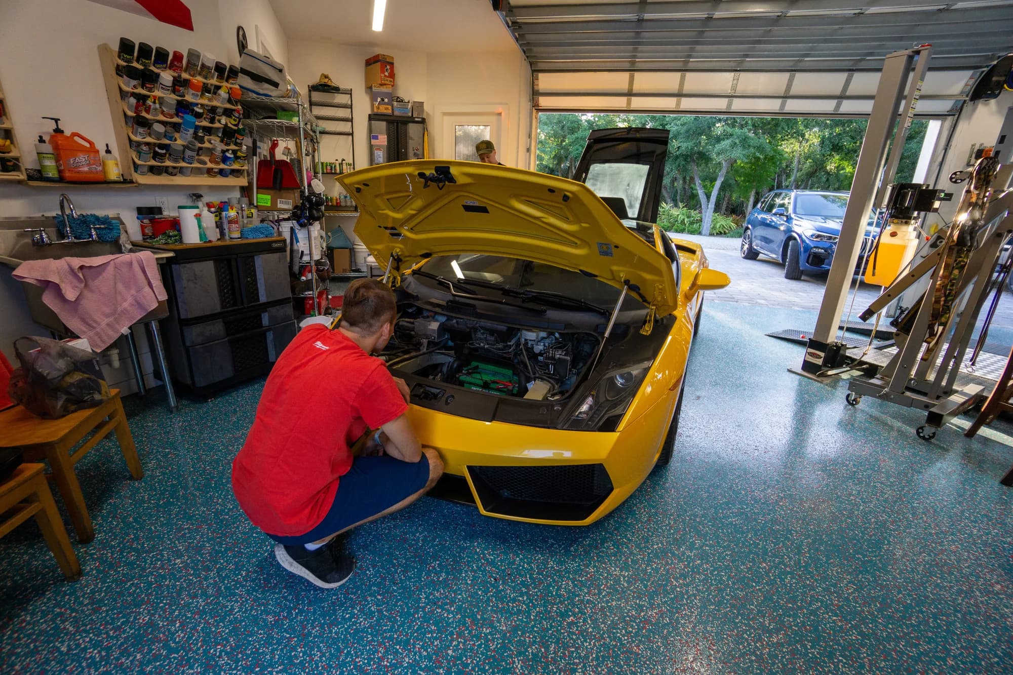A yellow Lamborghini Gallardo with the front hood open being worked on in the shop
